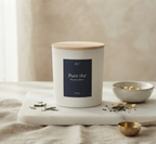 Bougie parfumée Pure thé JLT en cire végétale, présentée sur un socle clair avec des feuilles de thé et des éléments naturels.