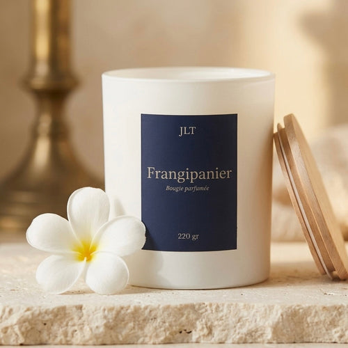 Bougie parfumée Frangipanier JLT avec fleur blanche et couvercle en bois dans une ambiance lumineuse et florale.