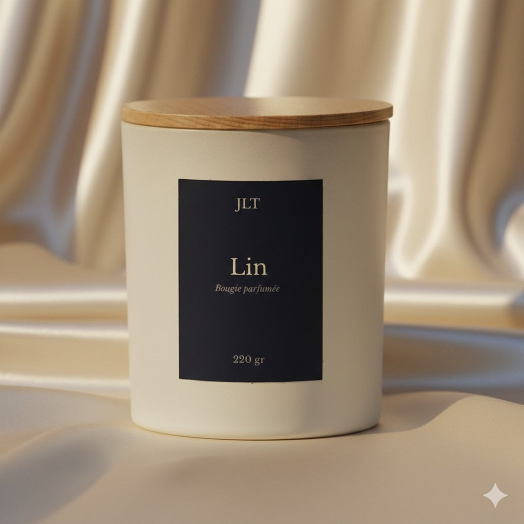 Bougie parfumée Lin JLT en verre blanc mat étiquette bleu nuit dans une ambiance lumineuse sur drap ivoire